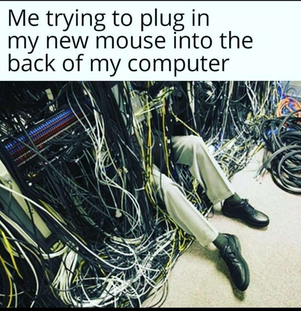 Man buried in tangled cables meme trying to plug new mouse into back of computer